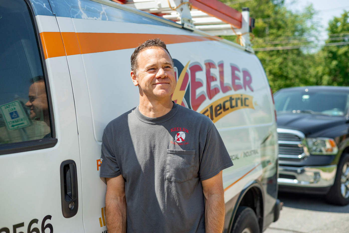 Owner Ryan Keeler poseed in front of Keeler Electric Van, smiling