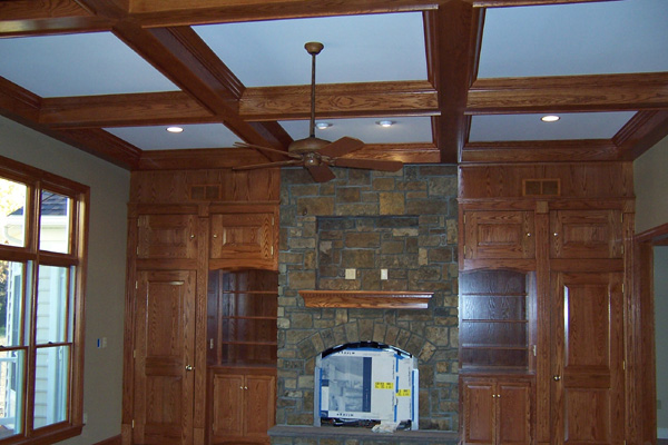 A fireplace in the center of a room with wooden cabinets.
